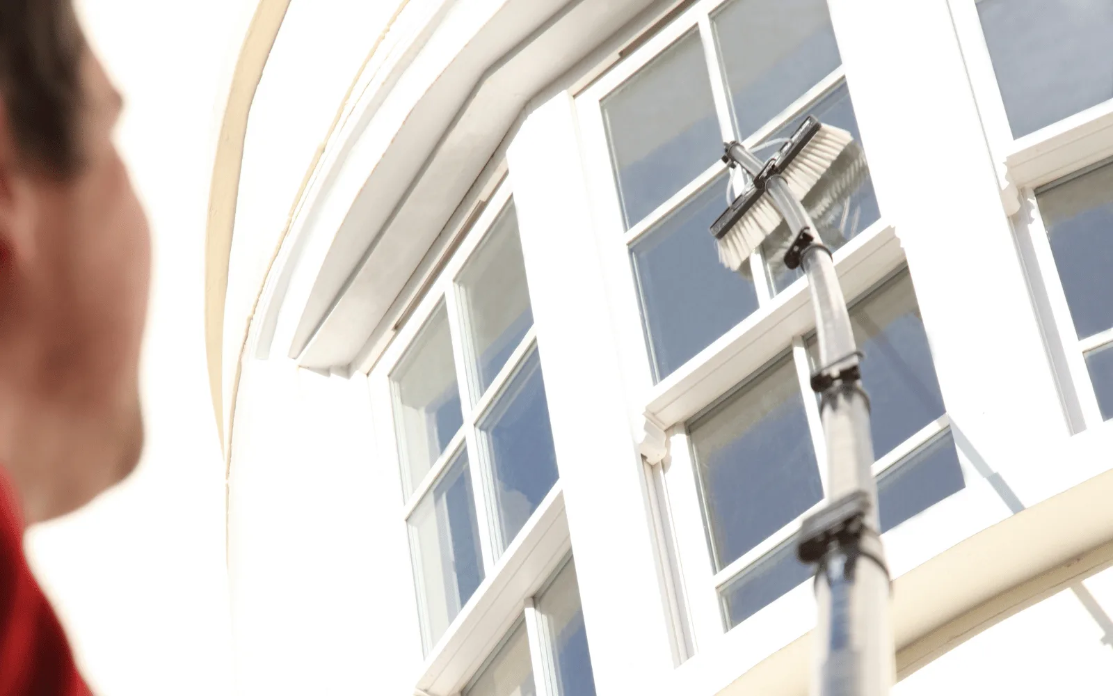 Bay Windows technician cleaning upper-story windows with a water-fed pole